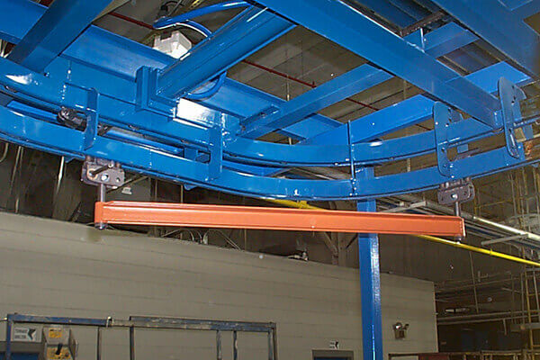 Enclosed track overhead conveyor with blue rail and carrier in a production facility