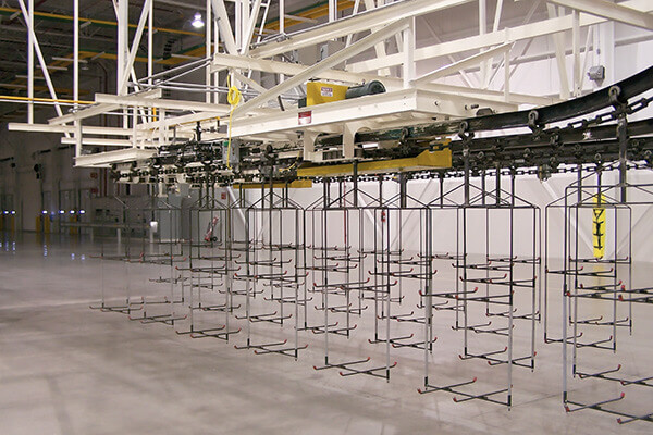 Specialty overhead conveyor with custom carrier frames in a high-clearance industrial facility