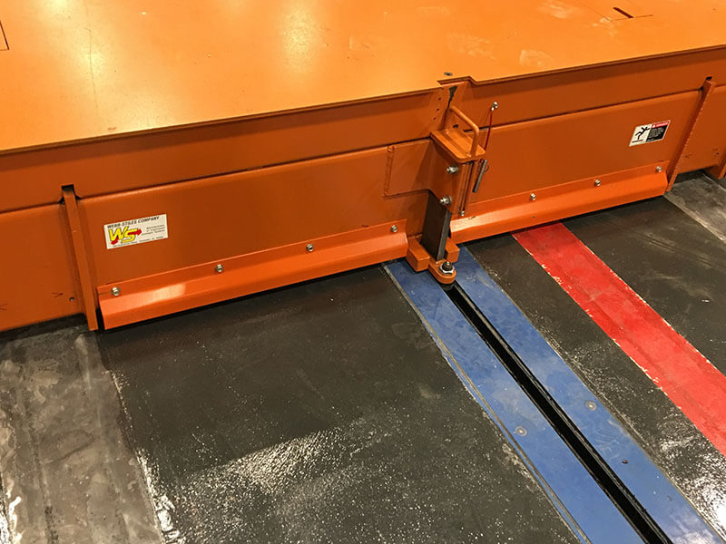 Floor-mounted towline conveyor system by Webb-Stiles with in-ground track and orange drive platform