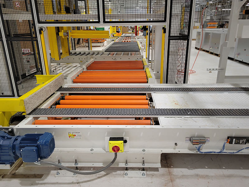 Custom assembly line conveyor system with orange motor-driven rollers and chain pop-up transfers for handling large refrigeration units