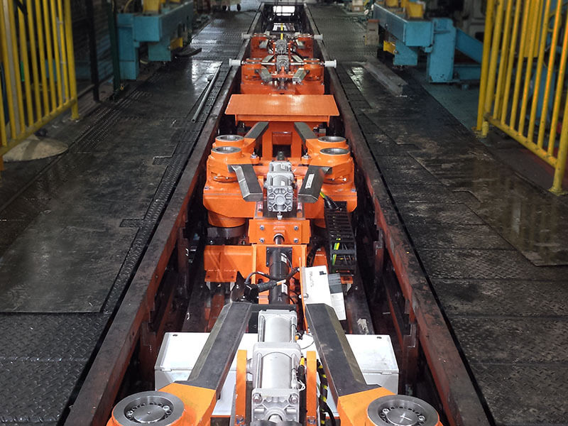 Custom glass body shuttle conveyor with rotating steel lift bars raising vehicle body for glass installation