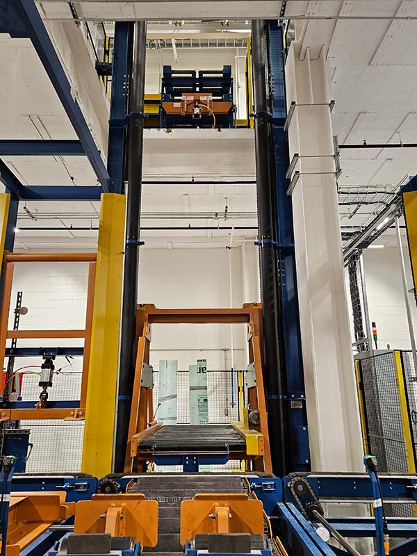 Custom rod and pallet handling system with vertical reciprocating conveyor (VRC) lifting pallets between floors for manual processing