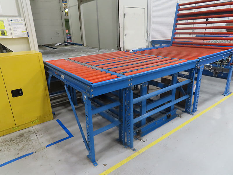 Custom slave pallet handling conveyor with red urethane-coated rollers and blue structural frame for heavy-duty material transport