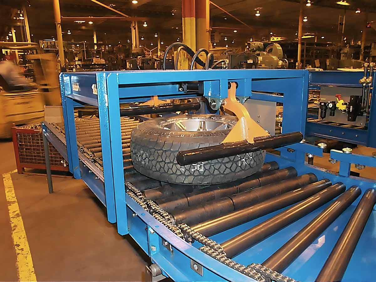 Automated stop station securing tires in place along conveyor lines for controlled load handling and staging.