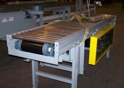 Belt driven live roller conveyor staged in shop with yellow guard, prepped for shipment after testing