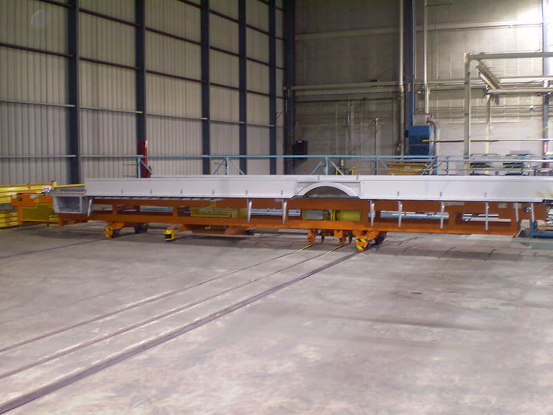 Heavy-duty transfer car used in school bus assembly plant with rail-mounted track system
