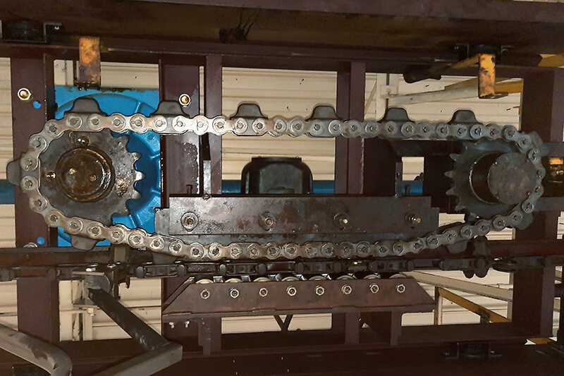 Underside view of a caterpillar drive showing chain loop, sprockets, and steel housing