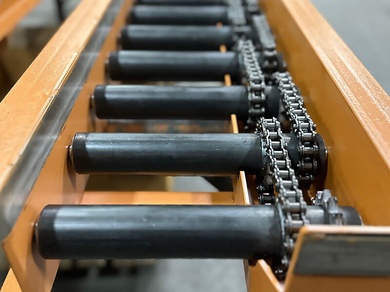 Chain-driven live roller conveyor with dual-sprocket rollers in a heavy-duty welded frame.