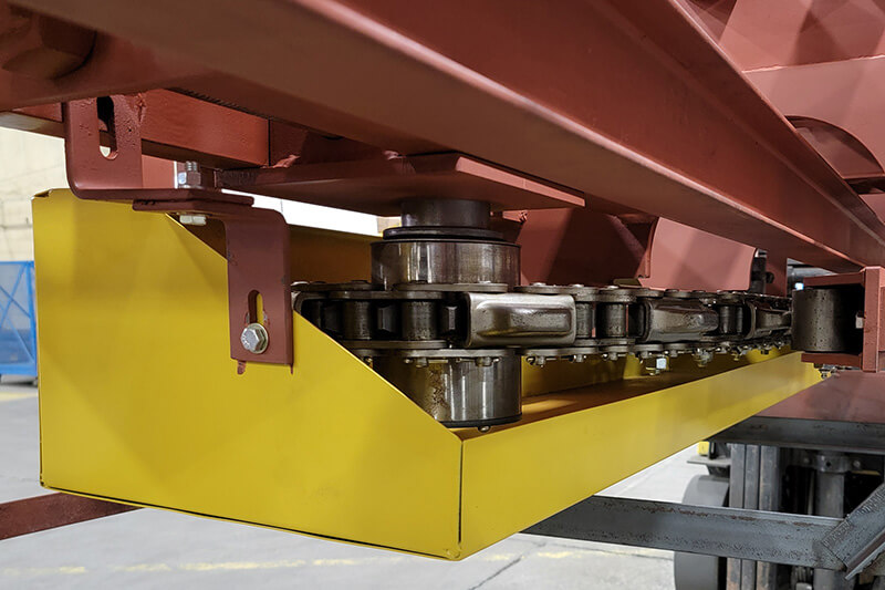 Yellow drip pan and guard beneath chain in a Webb-Stiles Caterpillar Drive assembly.