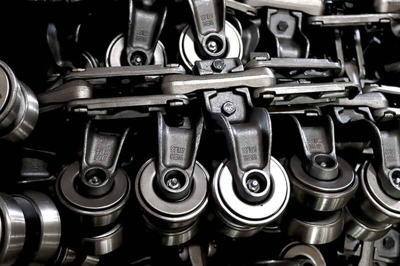 4-inch overhead conveyor trolley assemblies mounted to rivetless chain, shown with heavy-duty brackets and ball bearing wheels.